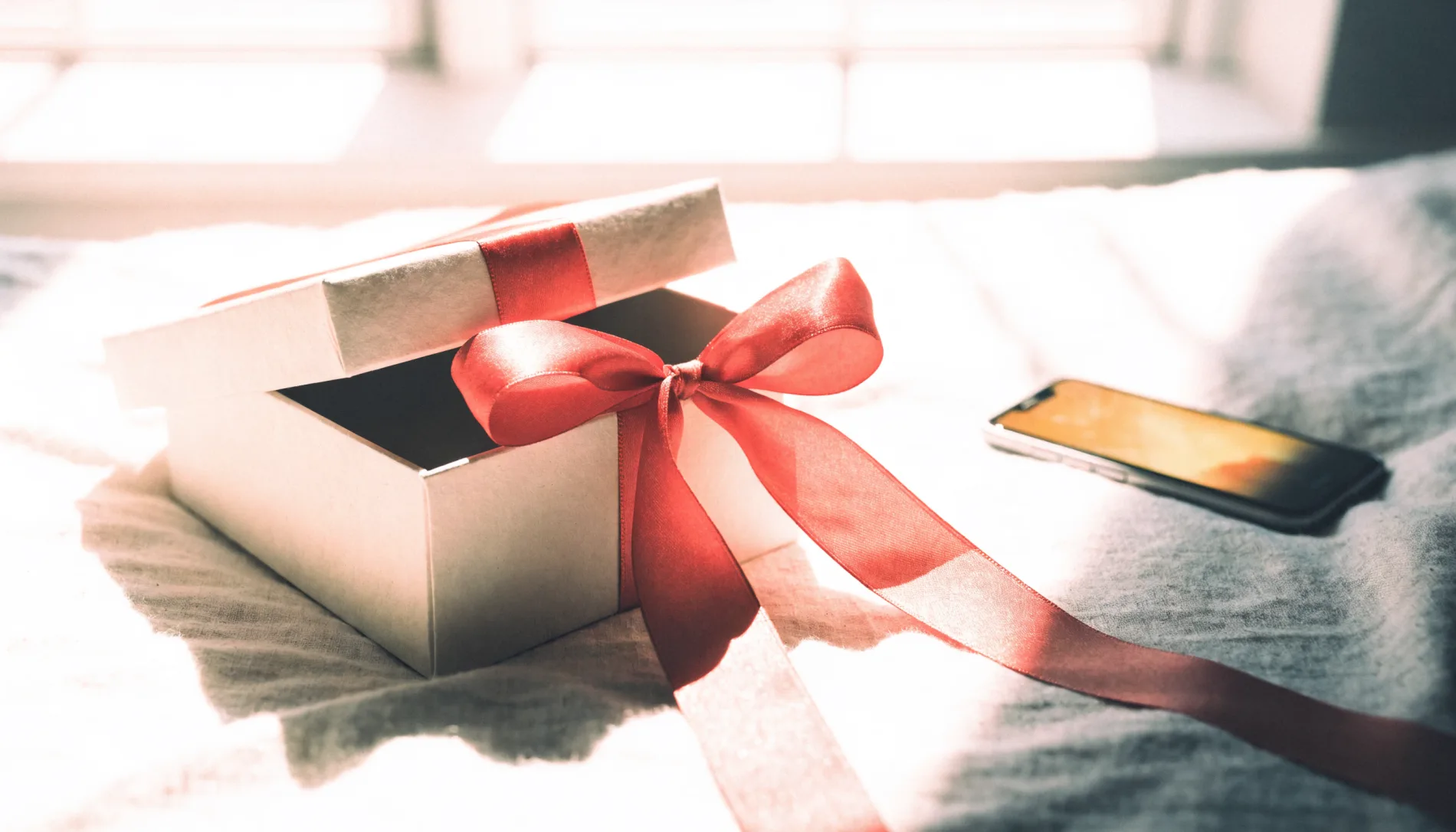 Gift box with a coral ribbon on linen