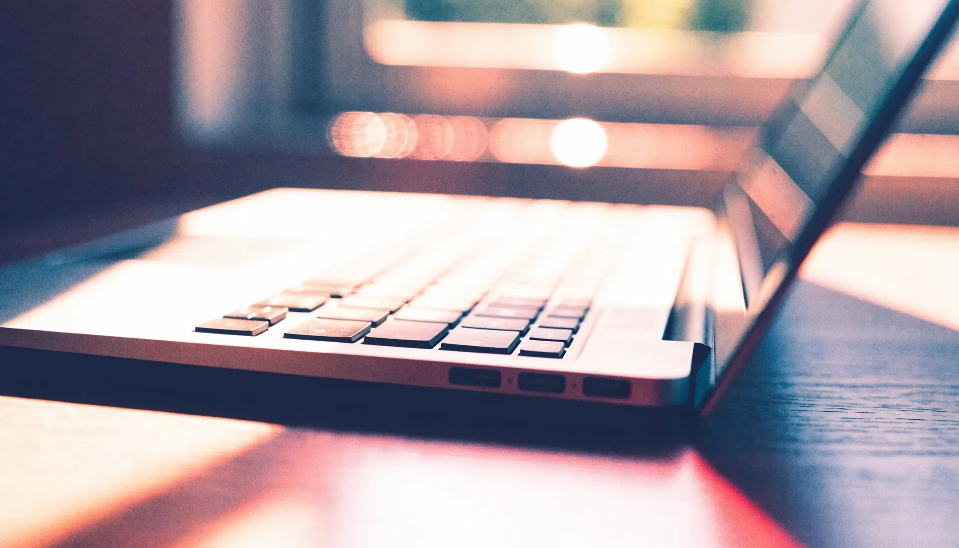 An open laptop catching warm window light