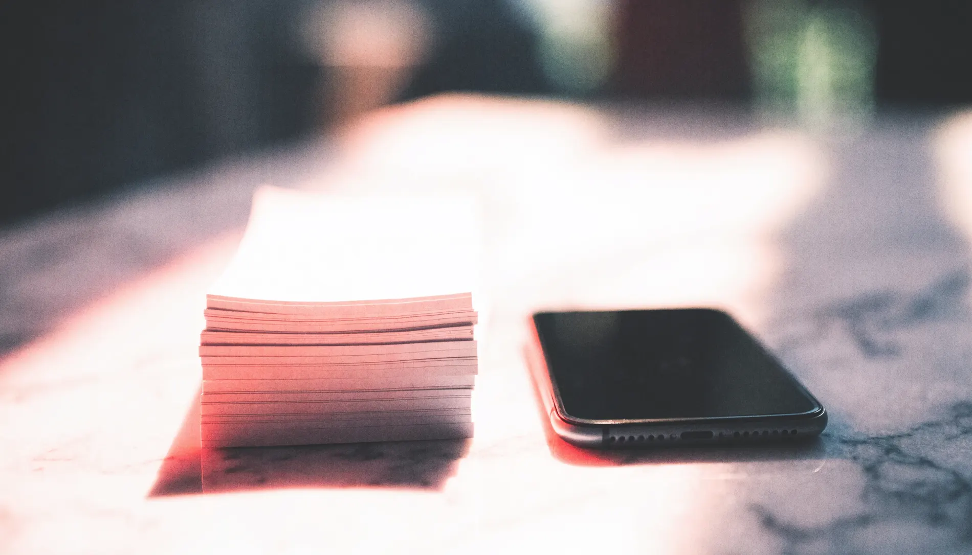 Paper slips beside a phone in raking light