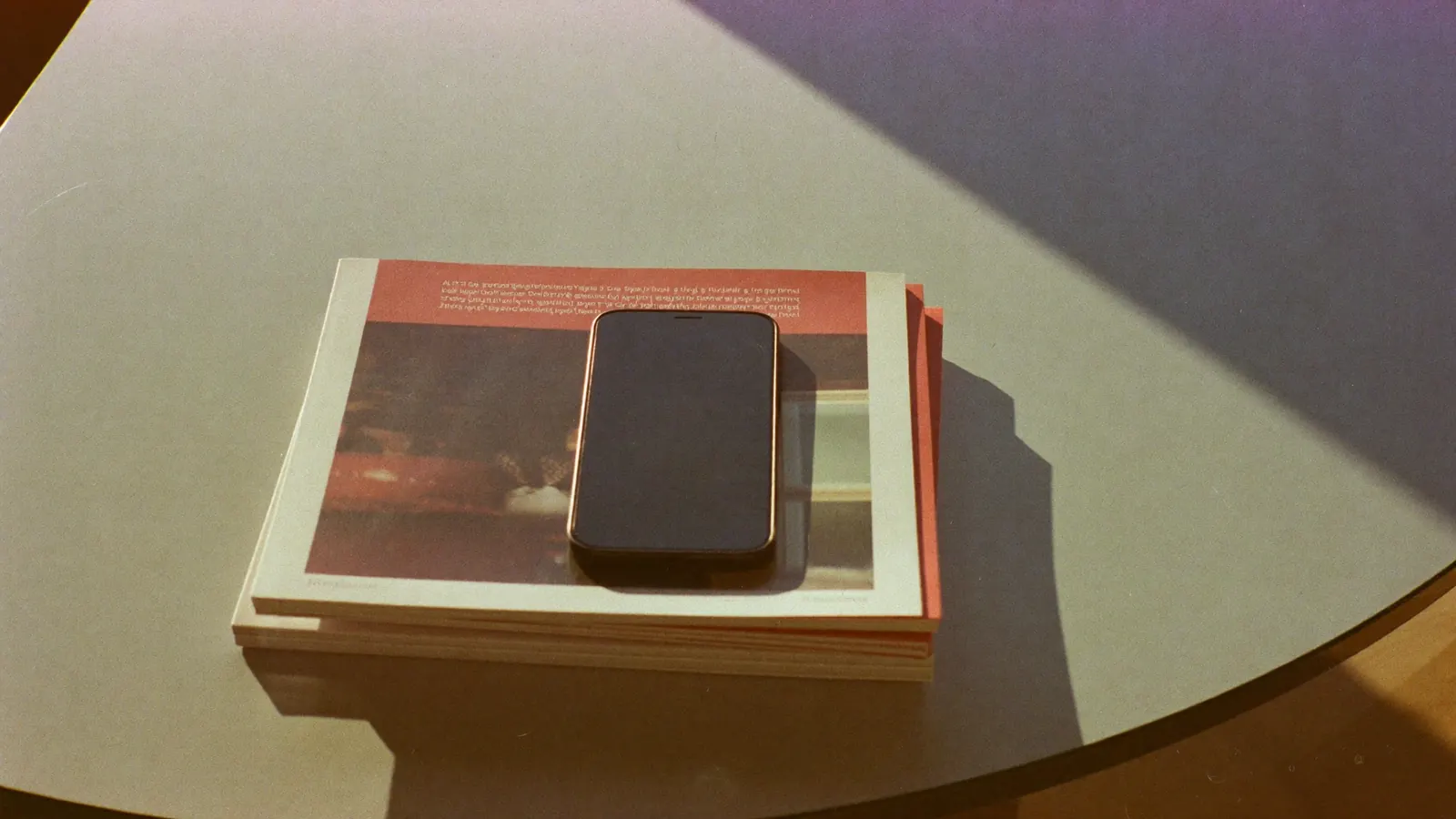 A phone on a stack of magazines on a coffee table, late afternoon sun