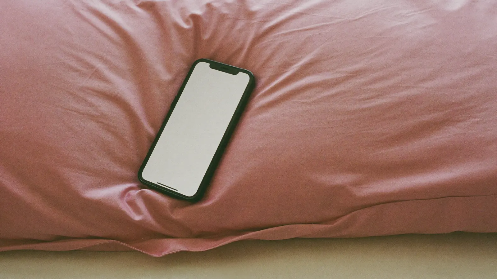 A smartphone on a pink satin pillow